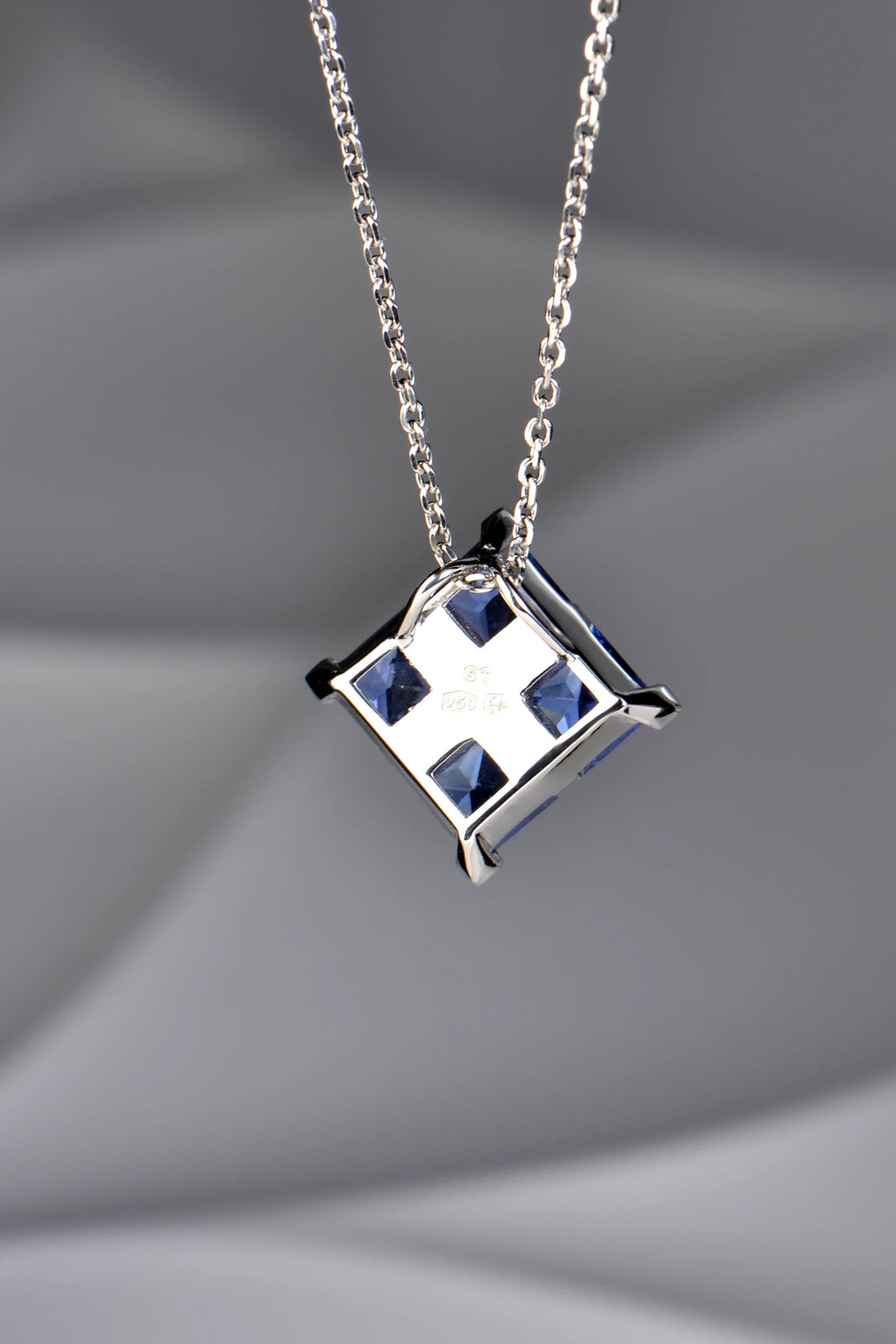 The back of a platinum Tartan pendant, showing the concealed double loop bail, open-back settings, and hallmarks.