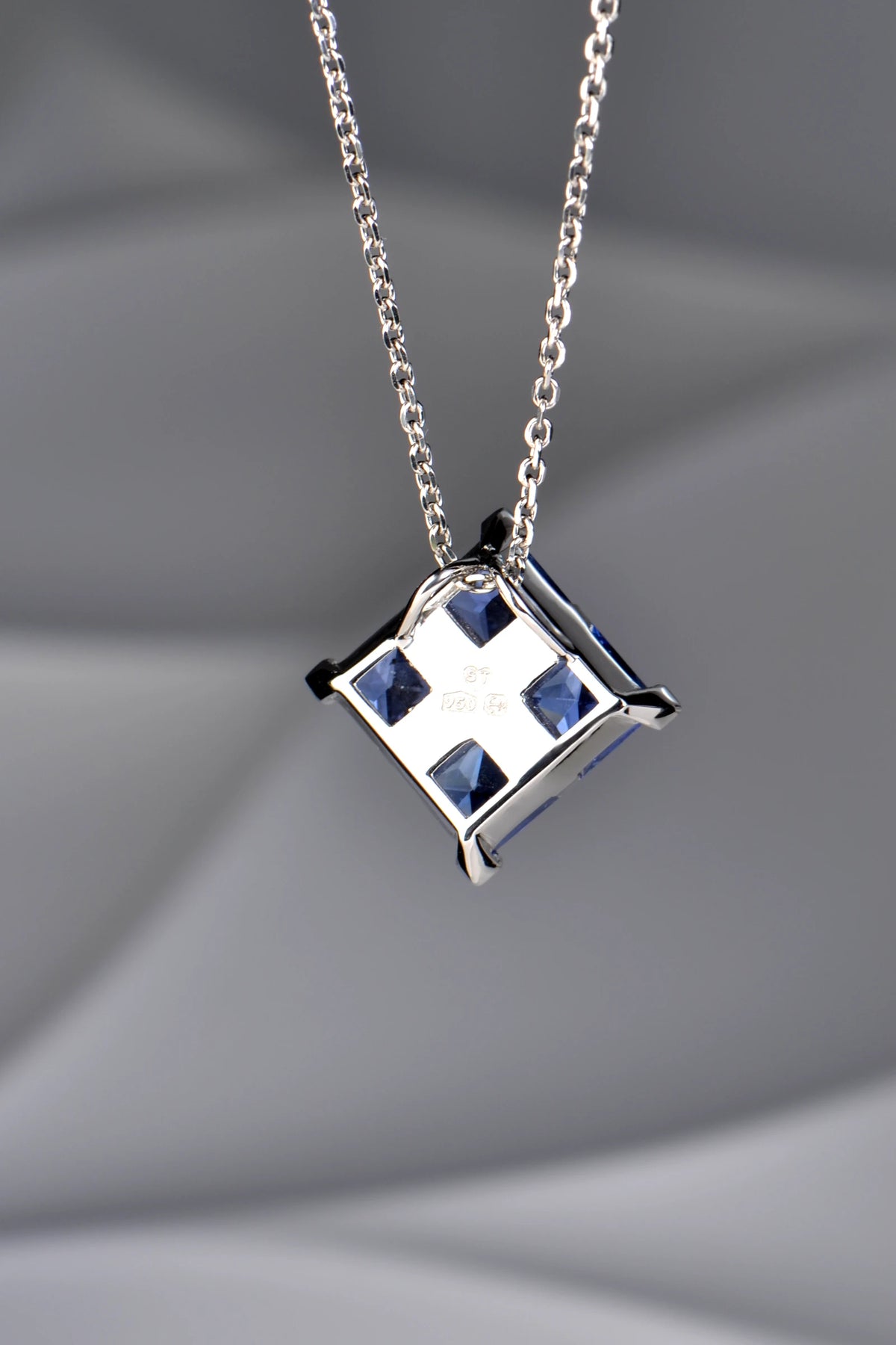 The back of a platinum Tartan pendant, showing the concealed double loop bail, open-back settings, and hallmarks.