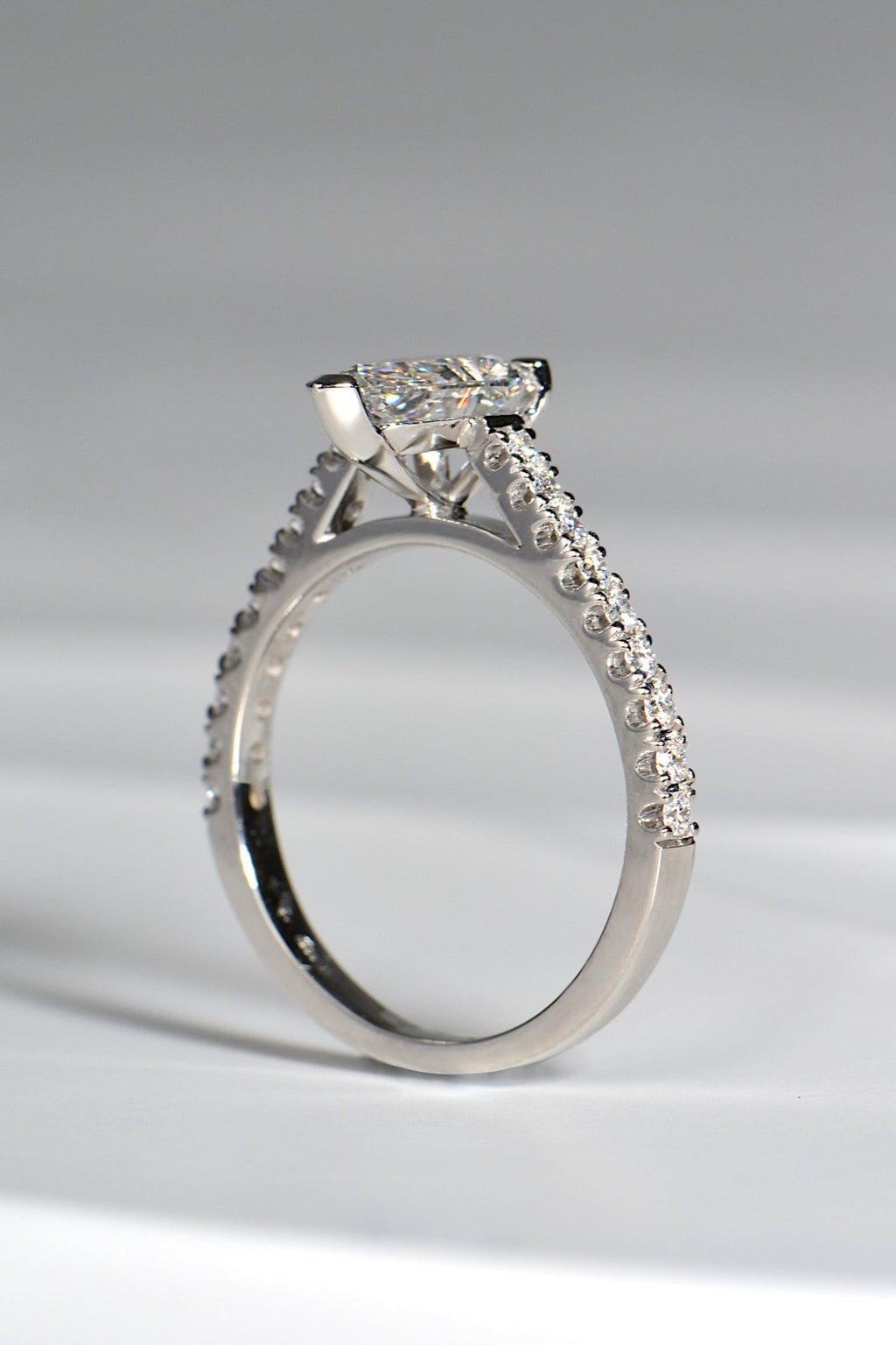 view of side of a pearl cut diamond engagement ring in platinum that has diamonds in the shoulders