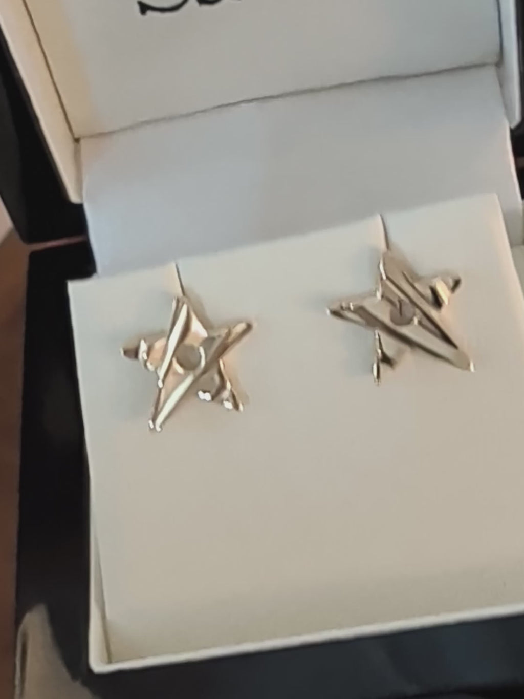 a pair of handmade 9ct gold star stud earrings with groved lines to make the stars look as if they have movement on the surface.