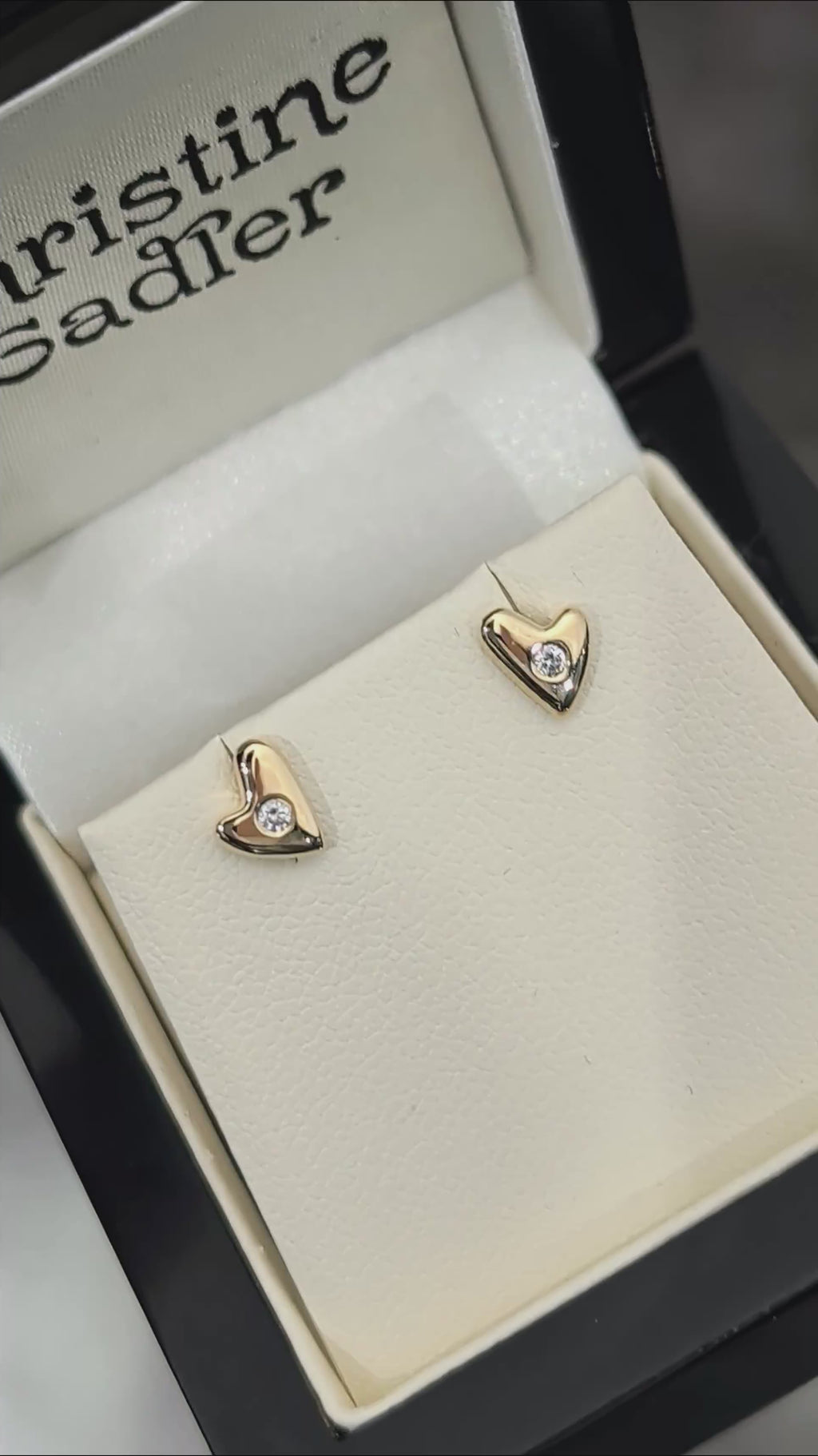 video of highly polished small gold heaert earrings set with a round diamond in the centre of each, twinkling in the light