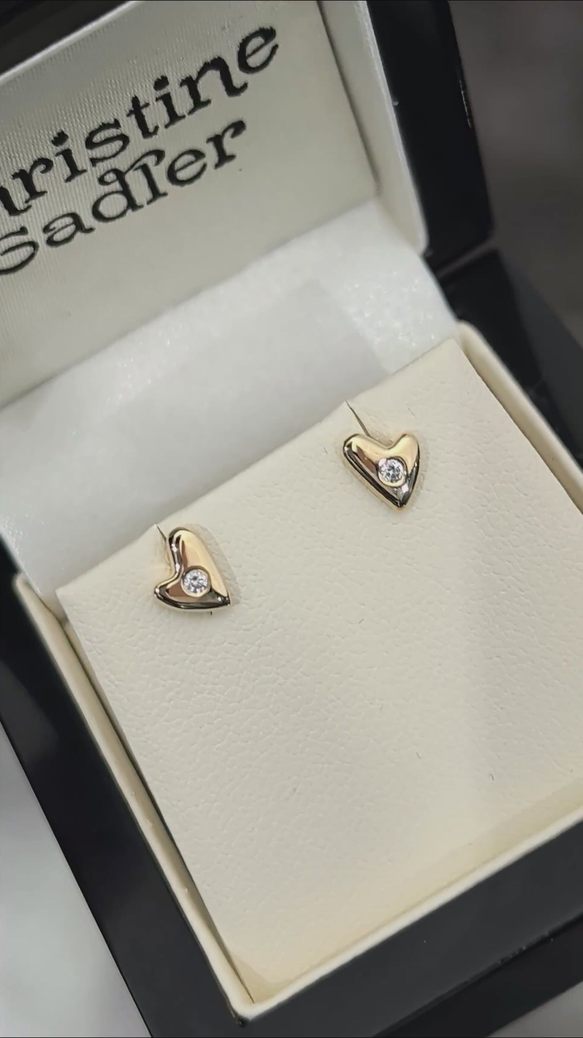 video of highly polished small gold heaert earrings set with a round diamond in the centre of each, twinkling in the light