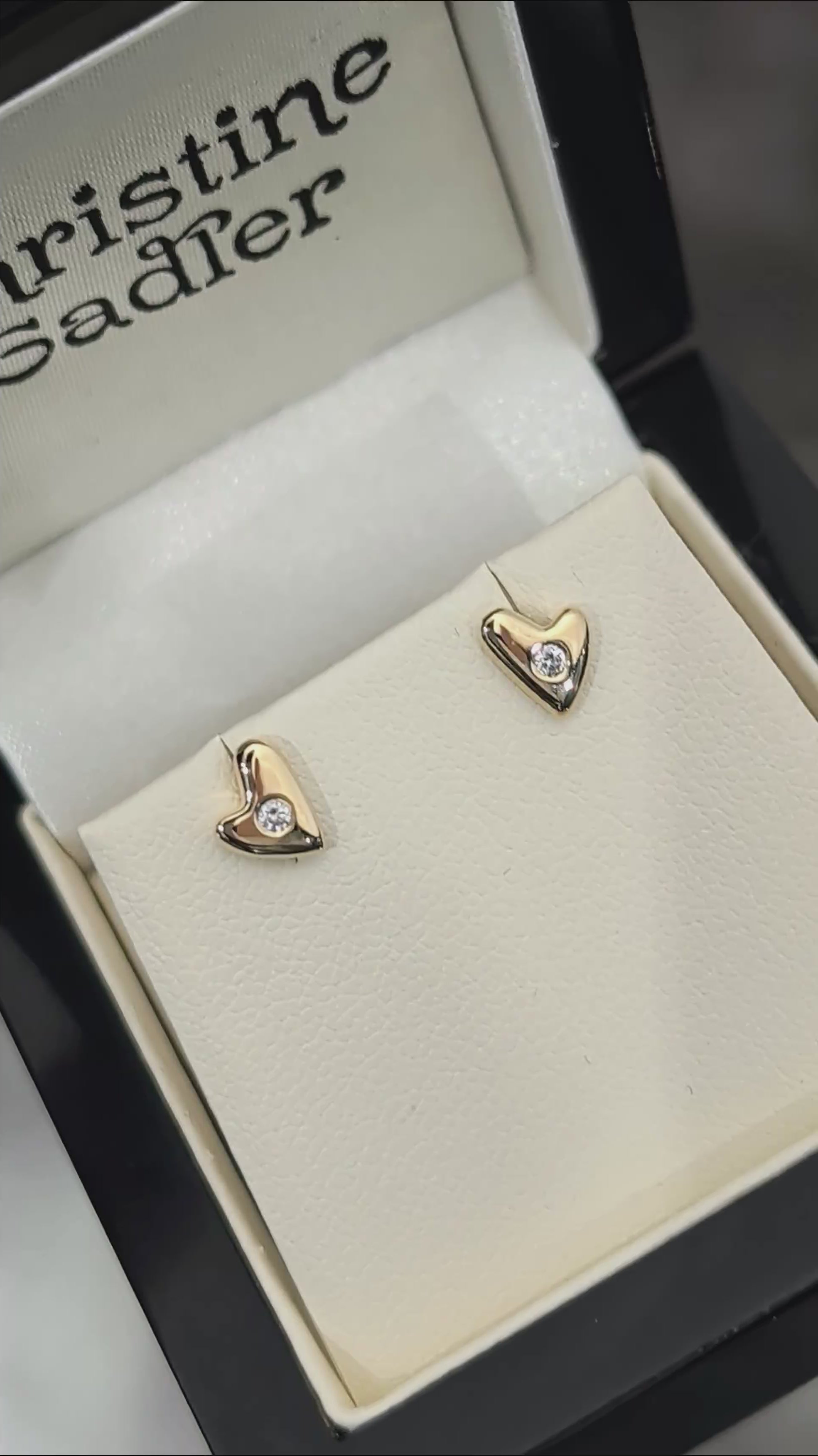 video of highly polished small gold heaert earrings set with a round diamond in the centre of each, twinkling in the light