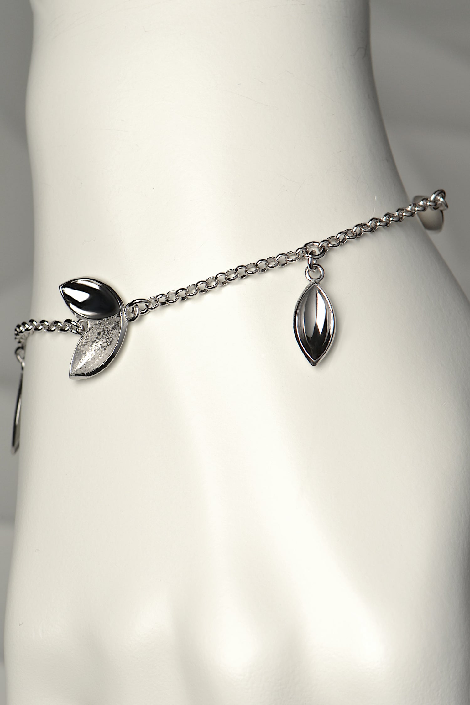 Modern silver charm bracelet with concave seed shapes in highly polished silver and contrasting textured finish. For each bracelet sold, a tree is planted - Christine Sadler