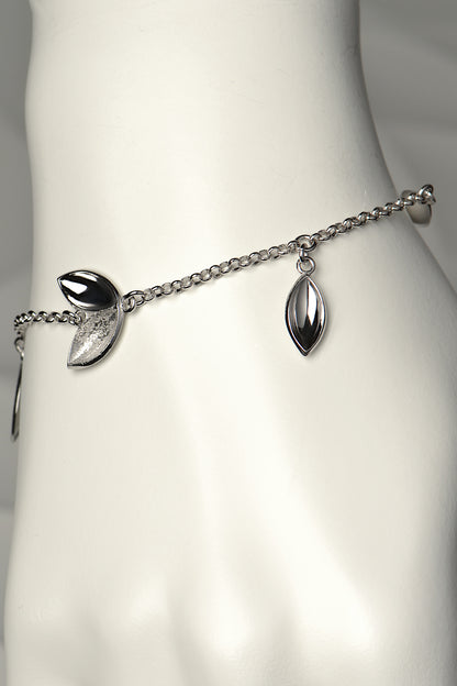 Modern silver charm bracelet with concave seed shapes in highly polished silver and contrasting textured finish. For each bracelet sold, a tree is planted - Christine Sadler