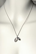 modern sterling silver handmade necklace with two concave seed shapes, one textured and one polished. This necklace is called The Promise because a tree is planted in Scotland for each one sold - Christine Sadler