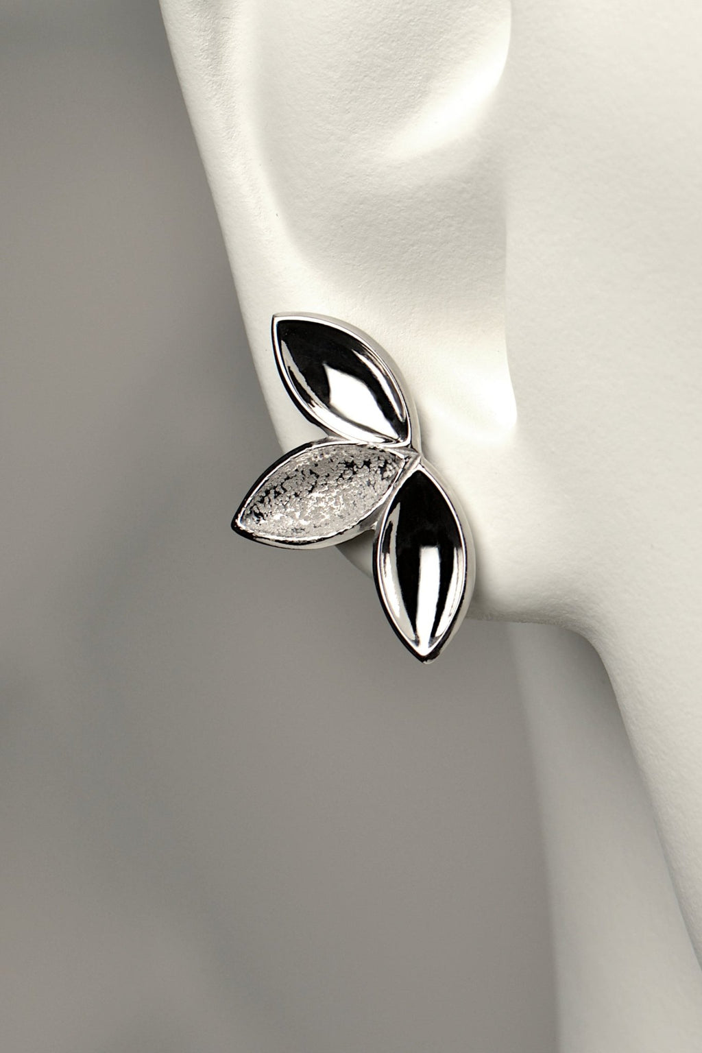 fairy like large silver stud earring made of three concave seed pod shapes in highly polished and contrasting modern textured finishes. The Promise jewellery collection from Christine Sadler plants a tree for every piece sold.