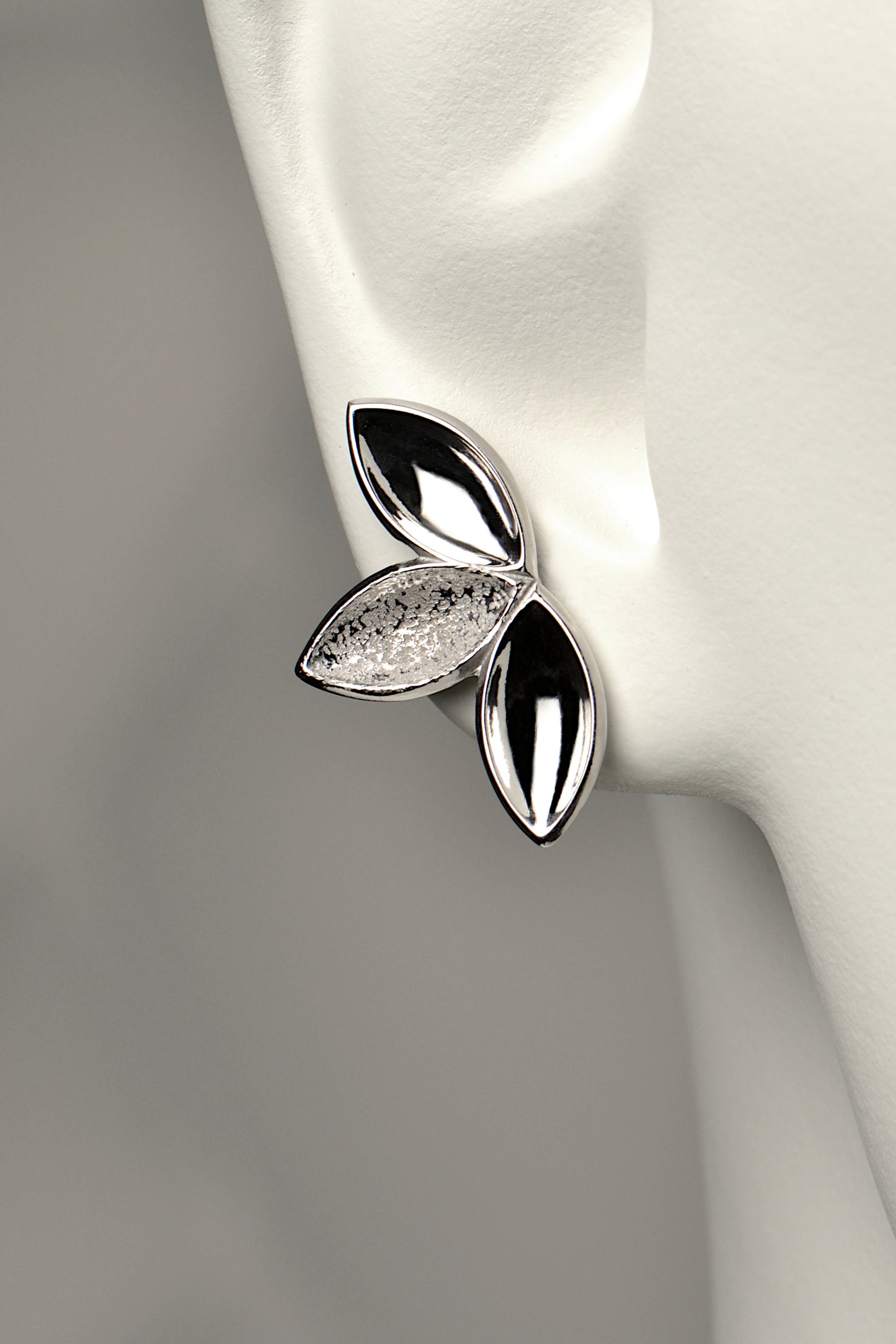 fairy like large silver stud earring made of three concave seed pod shapes in highly polished and contrasting modern textured finishes. The Promise jewellery collection from Christine Sadler plants a tree for every piece sold.