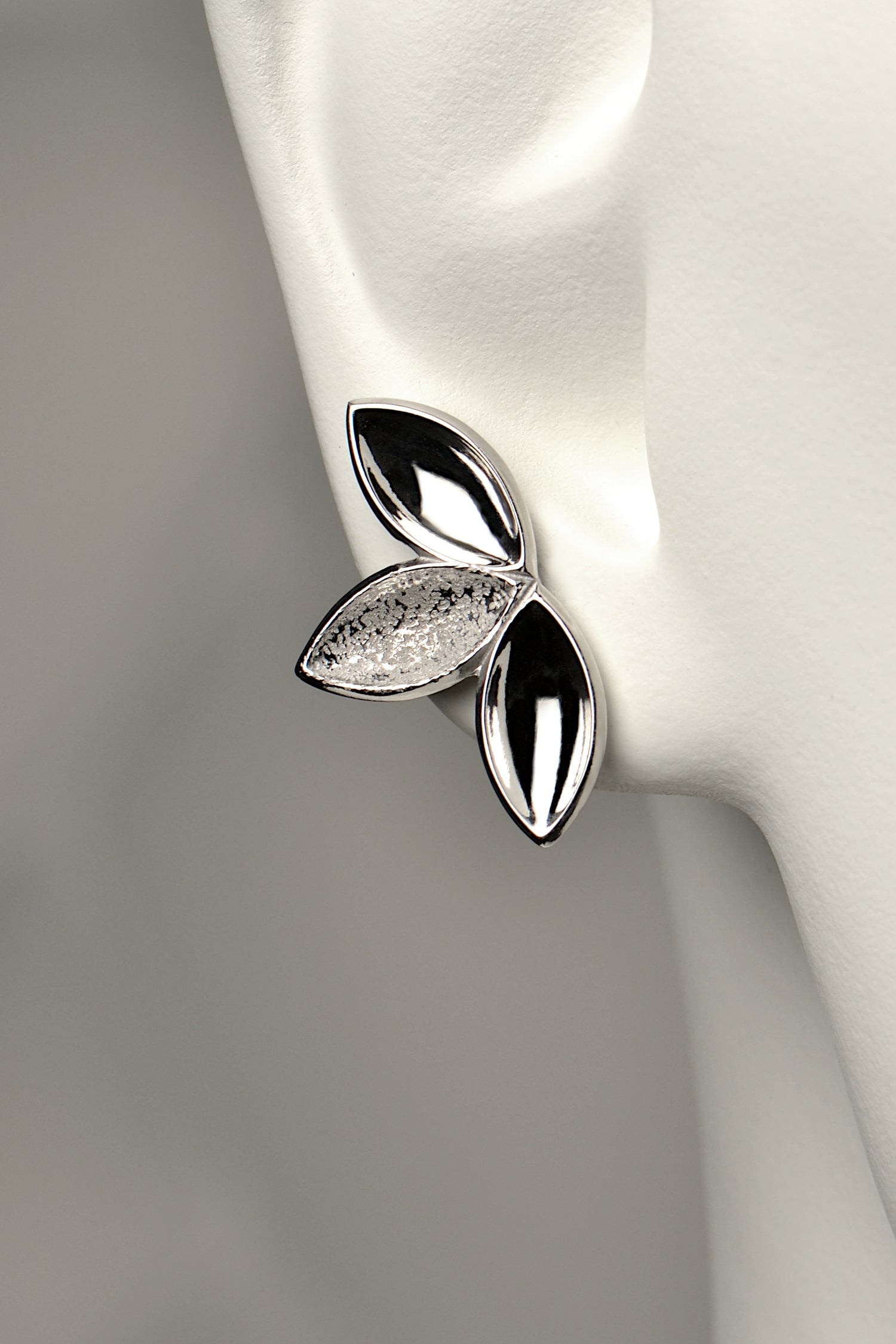 fairy like large silver stud earring made of three concave seed pod shapes in highly polished and contrasting modern textured finishes. The Promise jewellery collection from Christine Sadler plants a tree for every piece sold.