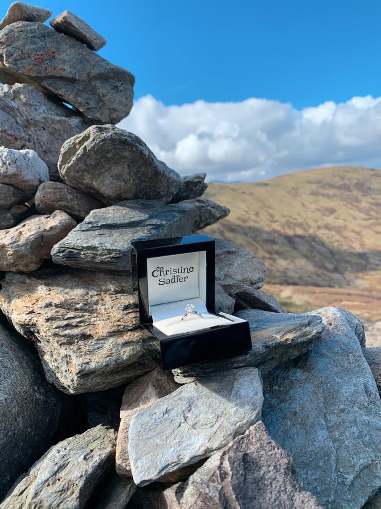 Exclusive luxury fine jewellery by british jewellery designer Christine Sadler. The image shows an engagement ring in a jewellery box on a cairn in the Scottish highlands. 
