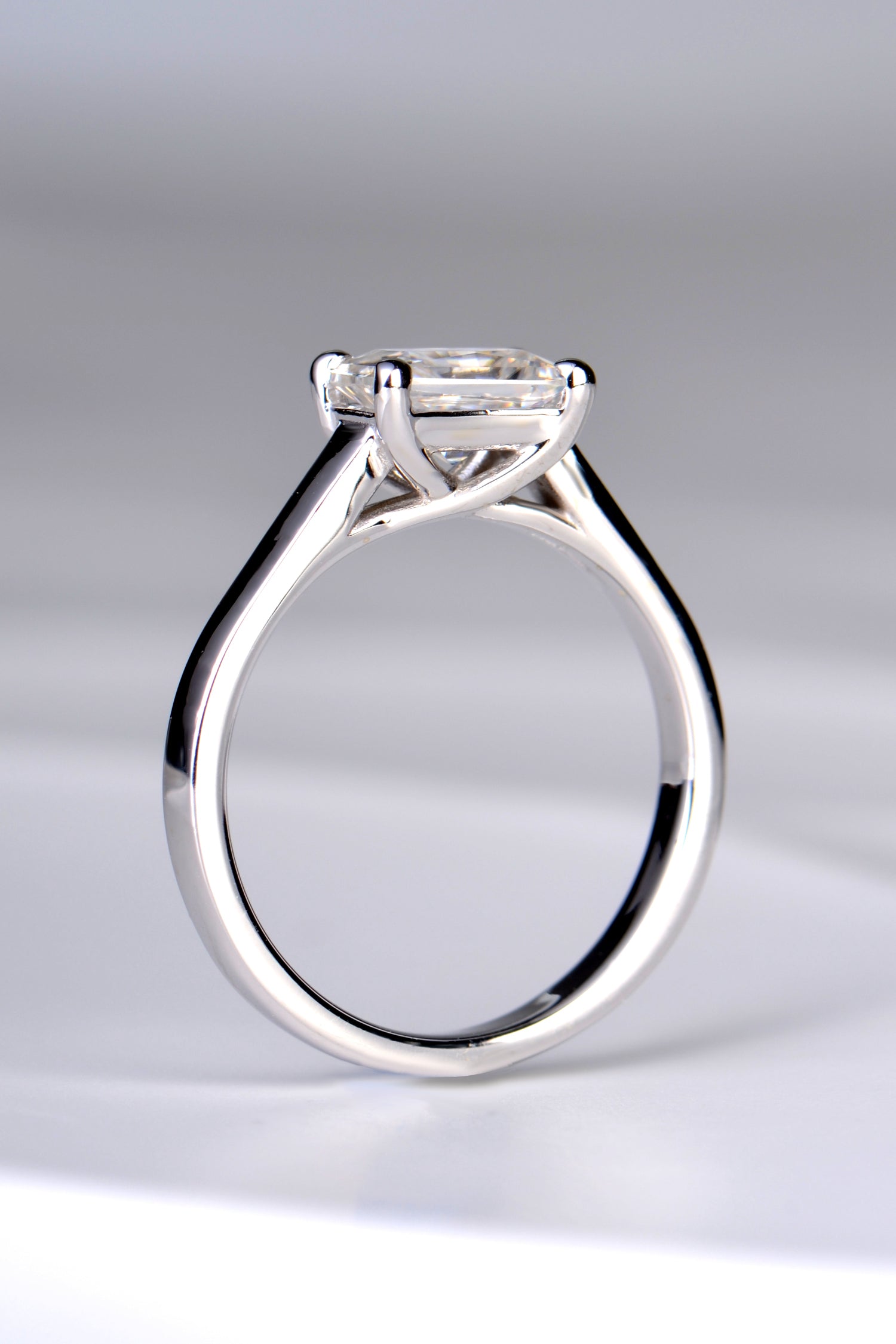 side view of the 7mm by 5mm rectangular moissanite ring showing a crossover design on the claws on the side of the ring which allow a straight band to sit next to it.