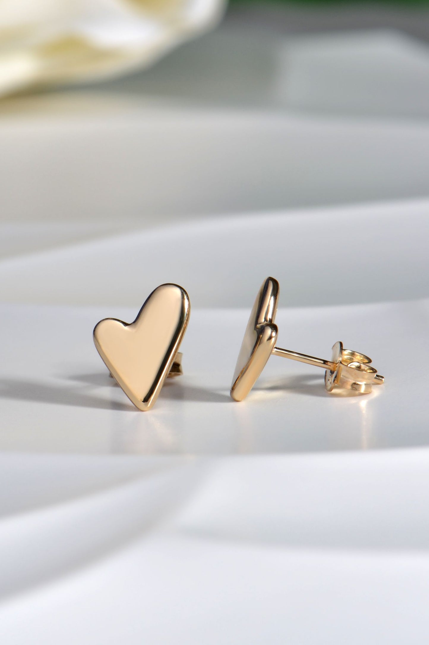 Designer gold heart-shaped earrings on a light surface