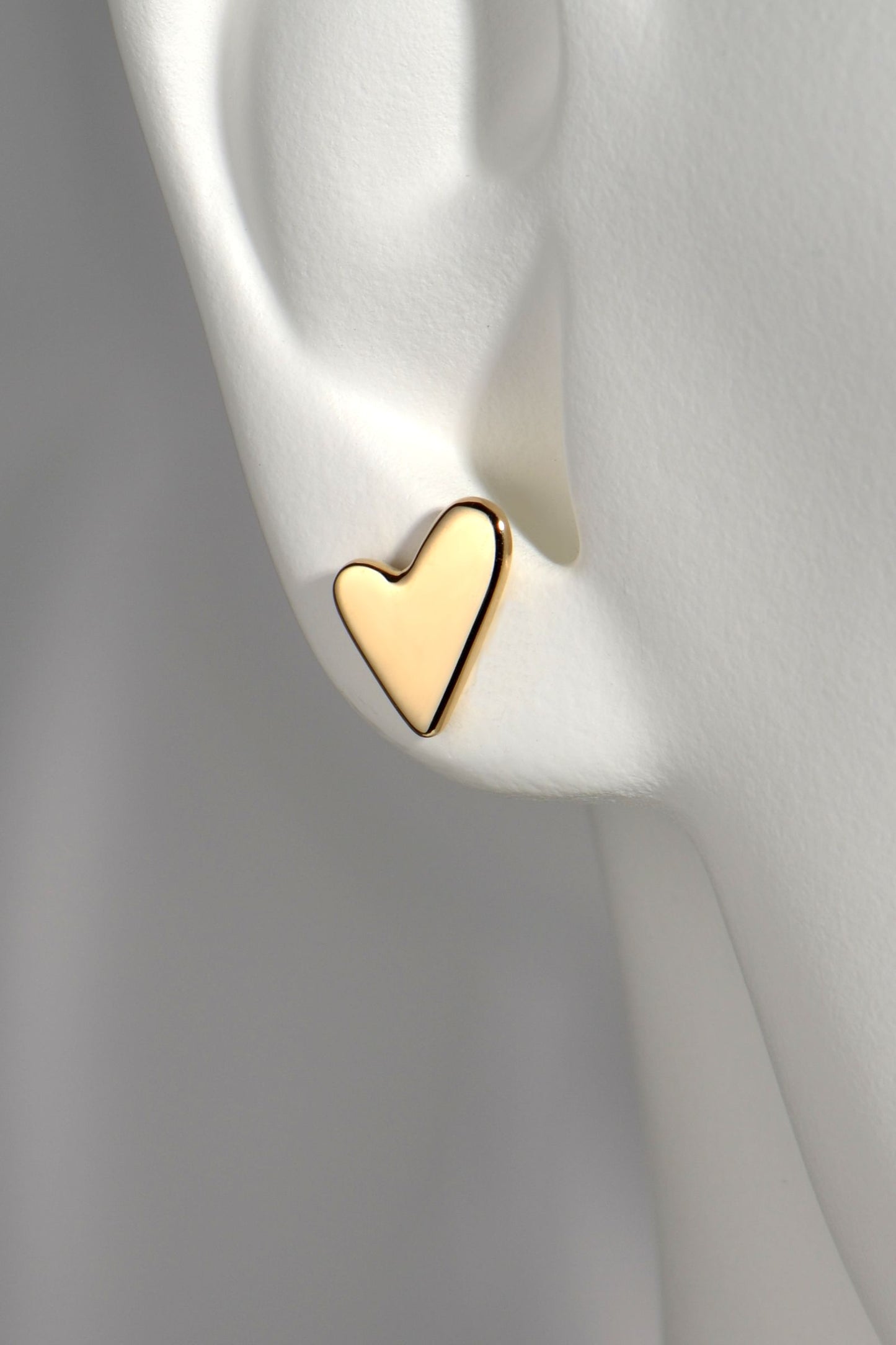 Gold heart-shaped earring on a white mannequin to show size and scale