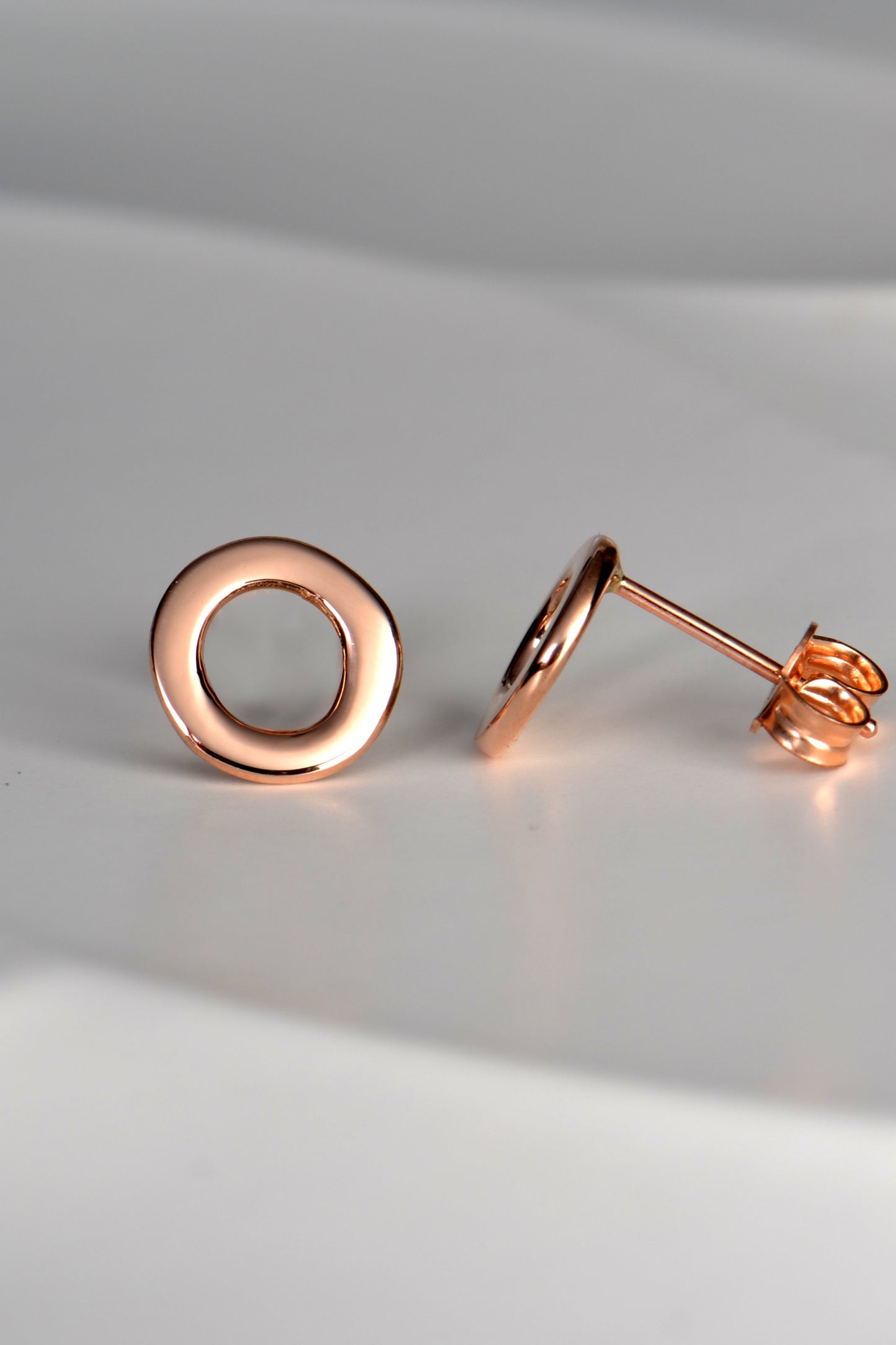 rose gold circle earrings shown side on so you can see that they are flat and sit close to the earlobe
