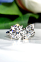 Hand crafted Platinum 950 Toi et Moi ring featuring a round brilliant and marquise lab-grown diamond set against a natural background of green leaves and flowers from Christine Sadler