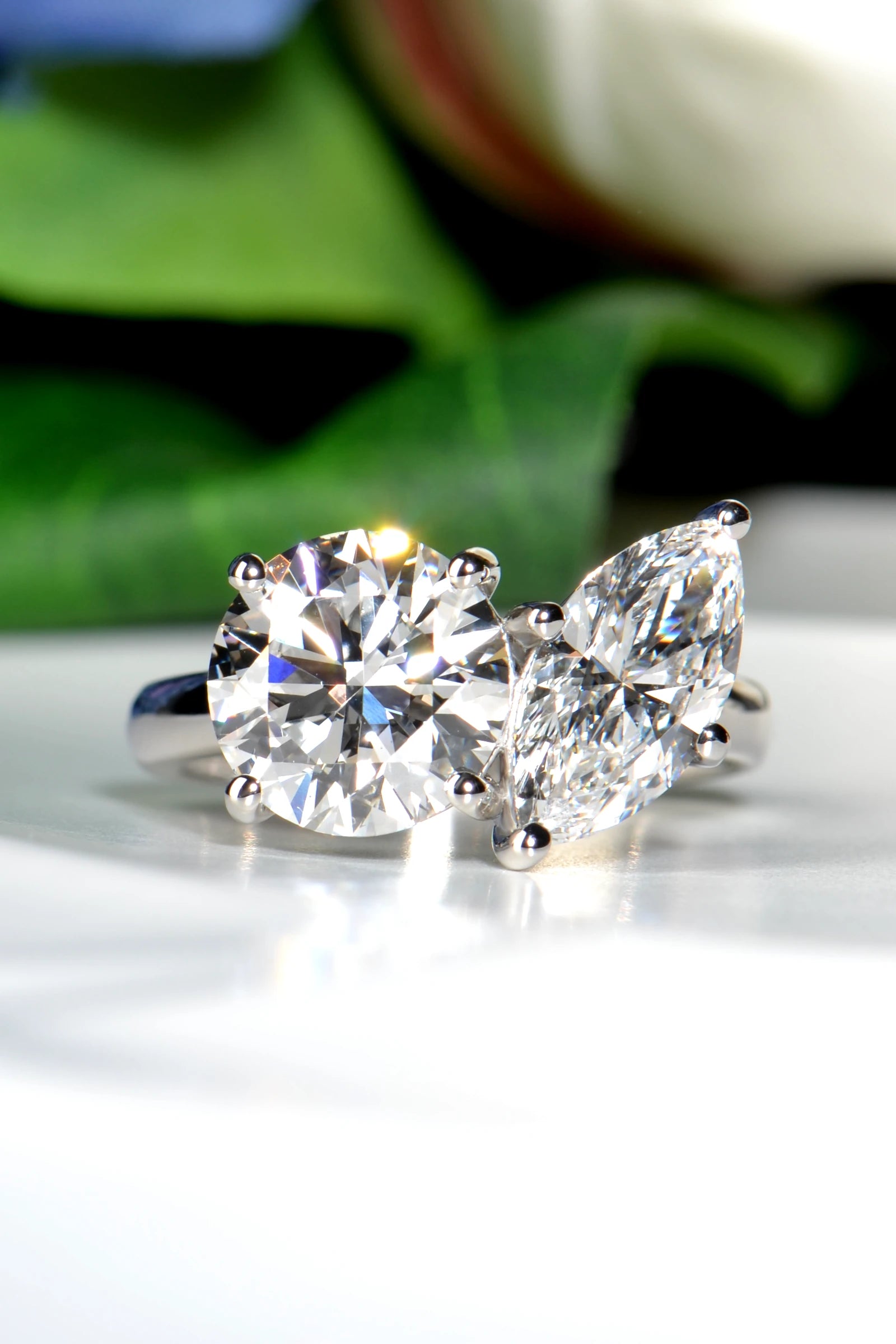 Hand crafted Platinum 950 Toi et Moi ring featuring a round brilliant and marquise lab-grown diamond set against a natural background of green leaves and flowers from Christine Sadler
