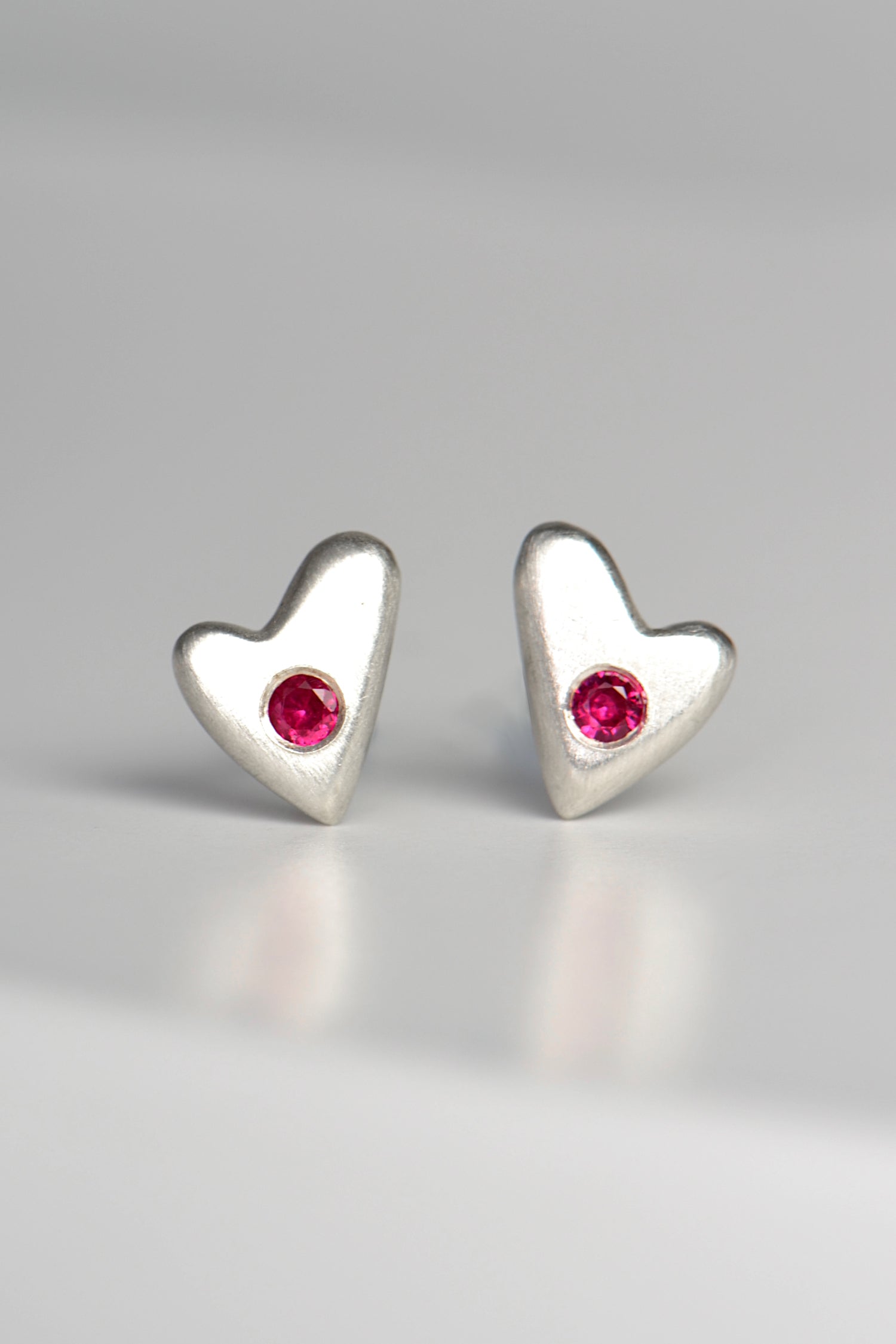 handmade designer silver heart earrings set with rubies by jewellery designer Christine Sadler