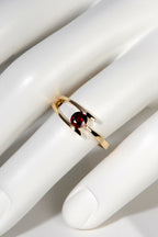 modern yellow gold ring with a round ruby on a mannequin hand