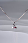 Small polished white gold heart necklace with a ruby displayed on white background from the From The Heart collection by Christine Sadler