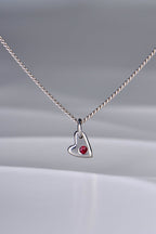 Small polished white gold heart necklace with a ruby displayed on white background from the From The Heart collection by Christine Sadler