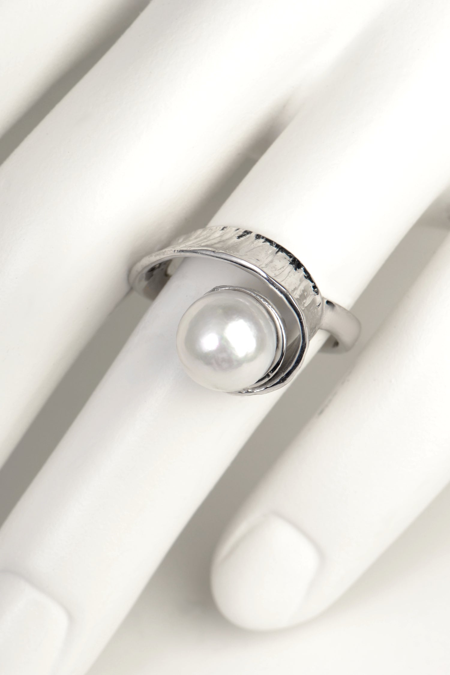 a round white pearl set in a swirling modern silver ring design by jewellery designer Jorge Revilla