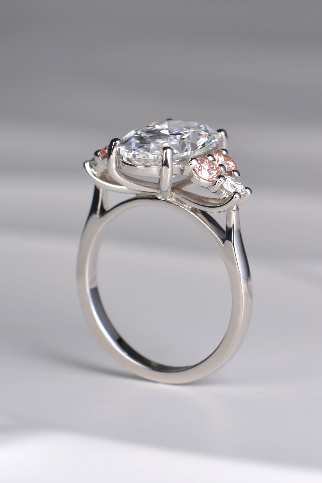 Rosé Spark platinum 950 ring viewed from below, showcasing the detailed setting and secure prong design beneath the central oval lab diamond and side stones