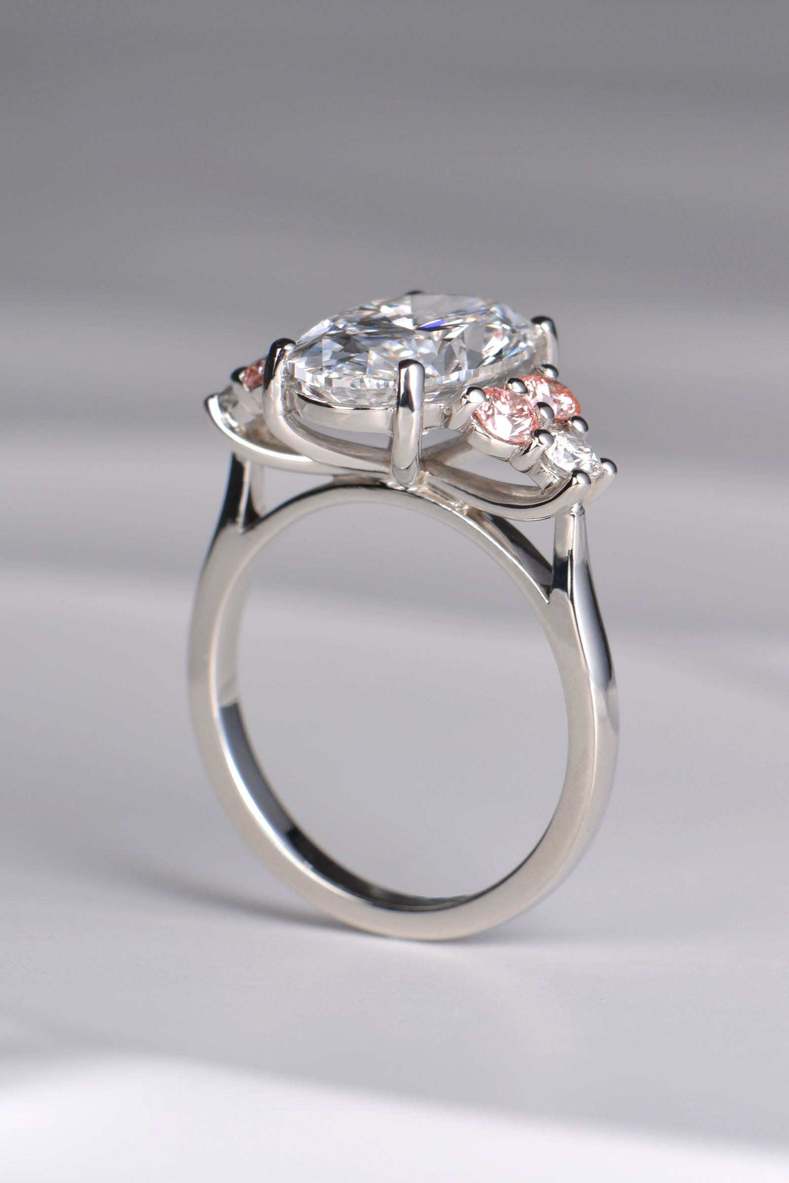 Rosé Spark platinum 950 ring viewed from below, showcasing the detailed setting and secure prong design beneath the central oval lab diamond and side stones