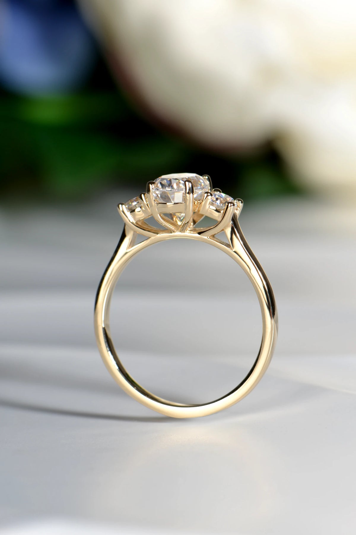Close-up view of a 9ct yellow gold three-stone moissanite ring showing the secure basket setting and snuggle fit detail. 