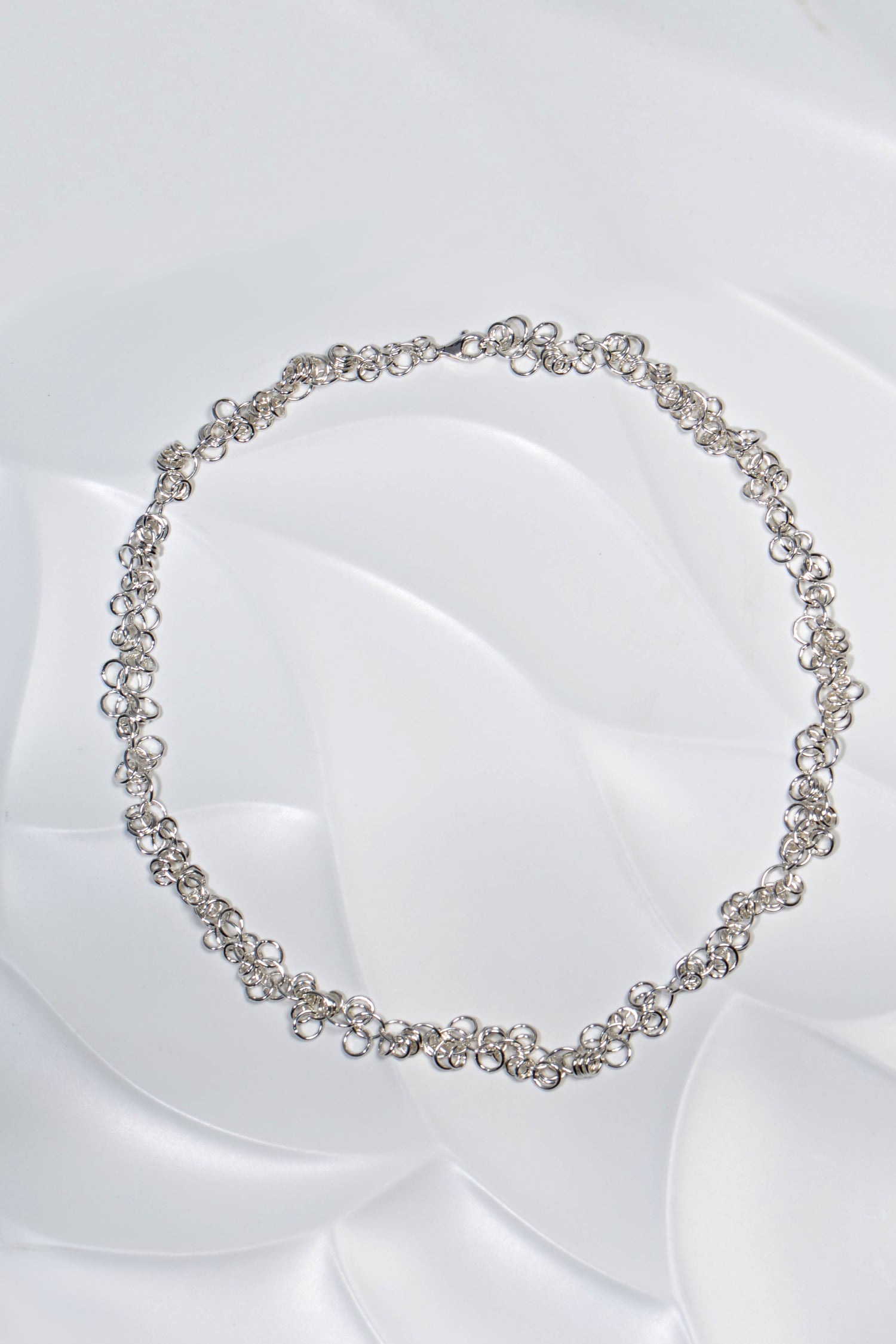 view of the full silver designer necklace flat on the surface