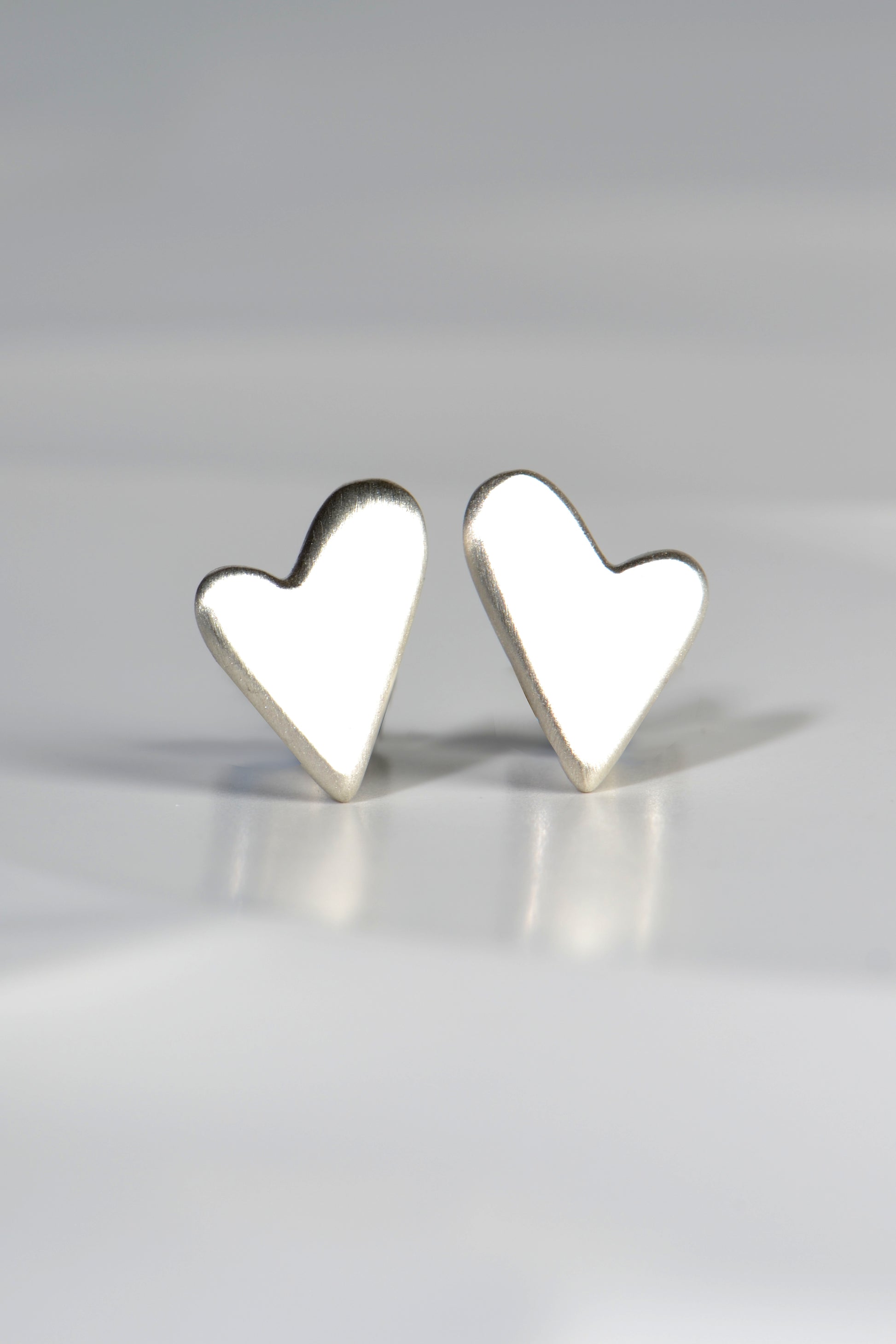 heart shaped designer earrings where the top of the heart is larger on one curved top bump than the other. They mirror each other to make a pair