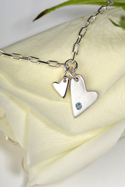 two heart silver bracelet set with an aquamarine gemstone on a white rose - Christine Sadler