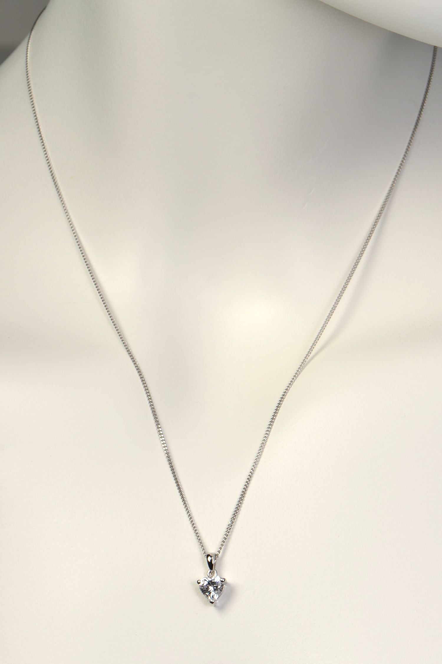 Silver necklace with a heart-shaped pendant on a mannequin.