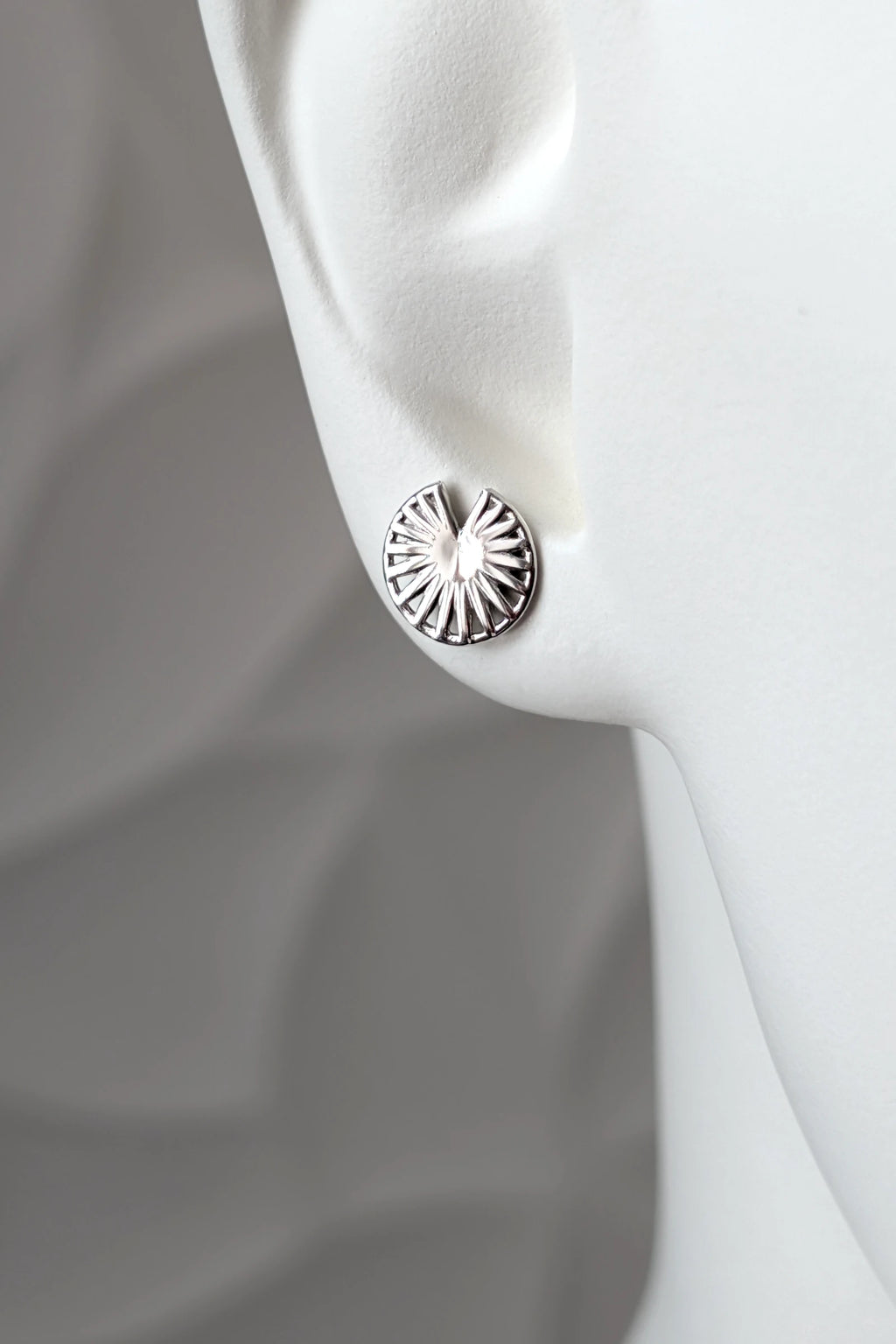 Sterling silver Break the Wheel talisman round stud earring shown on a mannequin ear to show size and scale