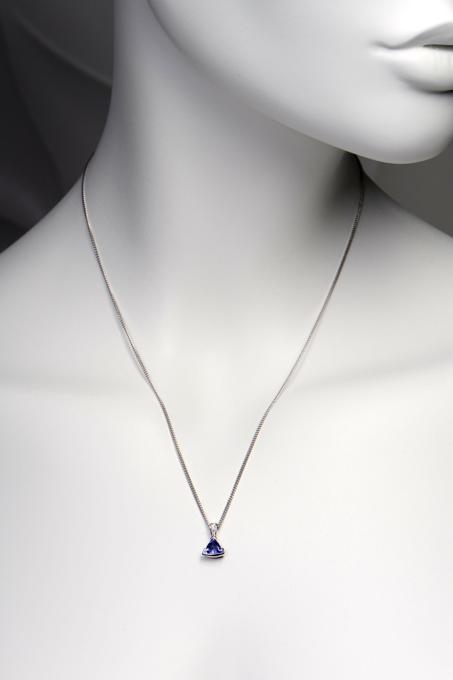 handmade high quality tanzanite and diamond designer necklace shown on a model. The pendant hangs about two inches below the collar bones