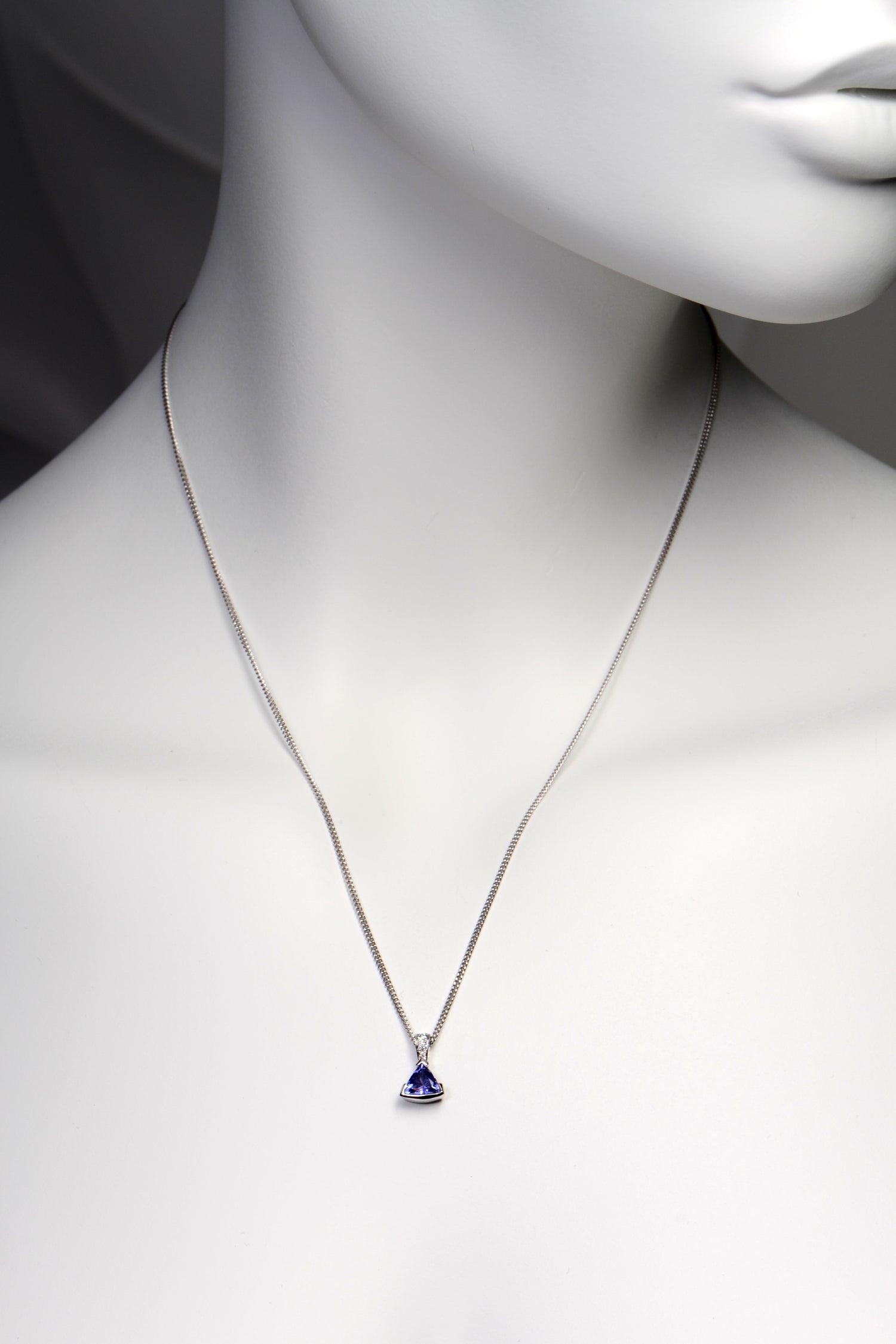 handmade high quality tanzanite and diamond designer necklace shown on a model. The pendant hangs about two inches below the collar bones