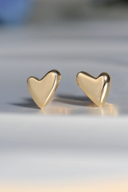 Gold heart-shaped earrings on a light gray background