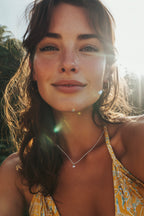 small white gold heart necklace set with a diamond worn by woman in yellow swimsuit - christine sadler