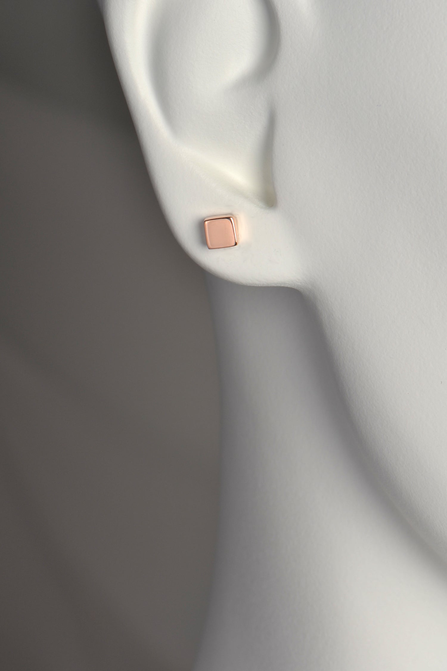 Picture of 5mm square designer earrings in an earlobe showing that they are petite and cover about half the earlobe