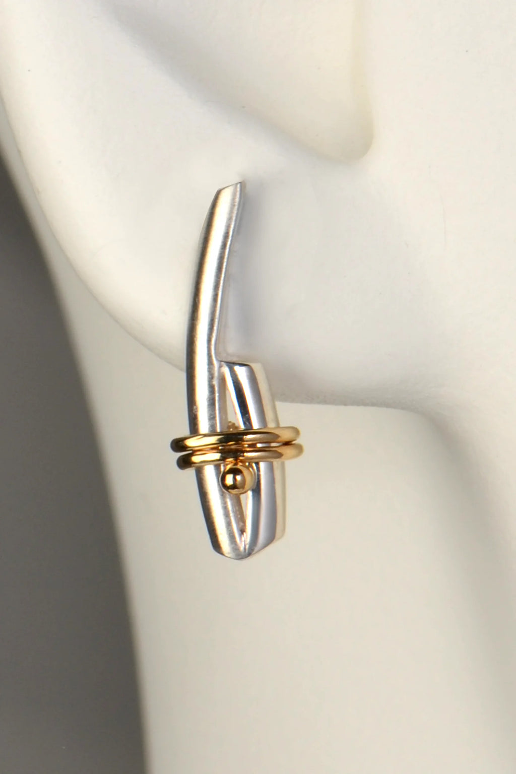 silver and yellow gold Stay Together earring in a model ear to show size and scale
