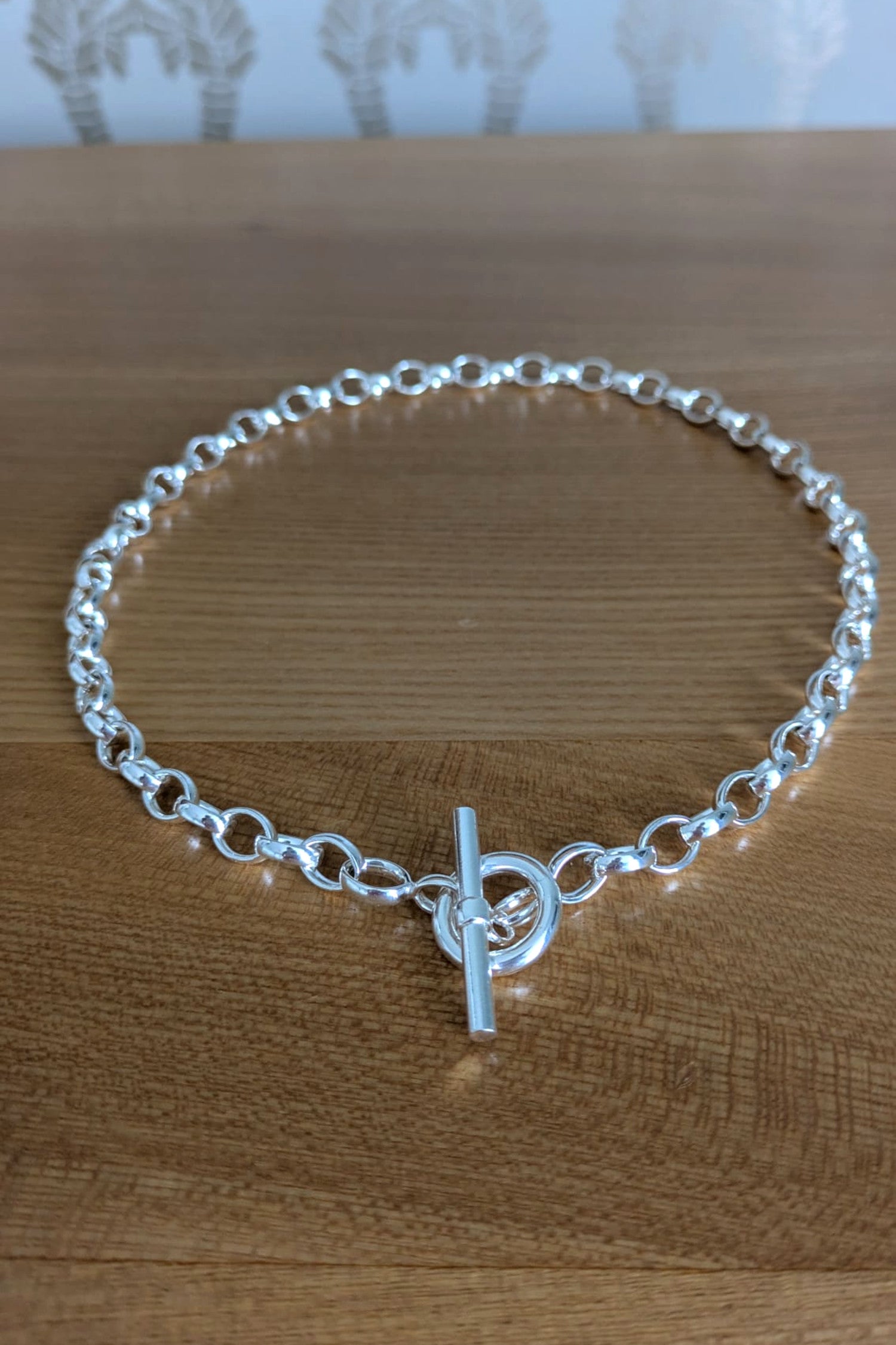 Sterling silver T-bar necklace with soldered links displayed on natural wood surface – secure and stylish design
