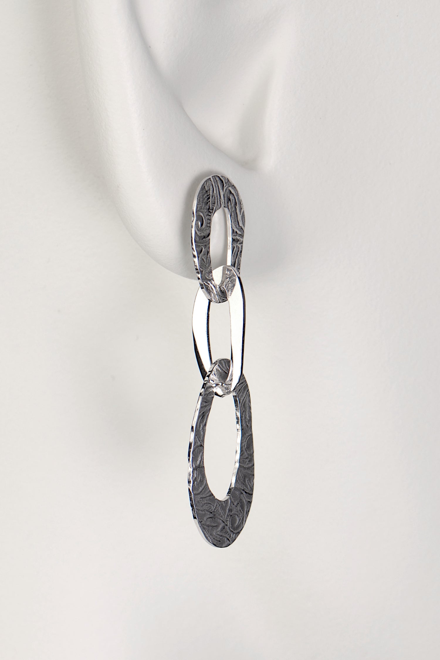 three interlocking organic oval links form a long drop silver earring with a textured pattern on the links inspired by the natural beauty of frost patterns - Christine Sadler