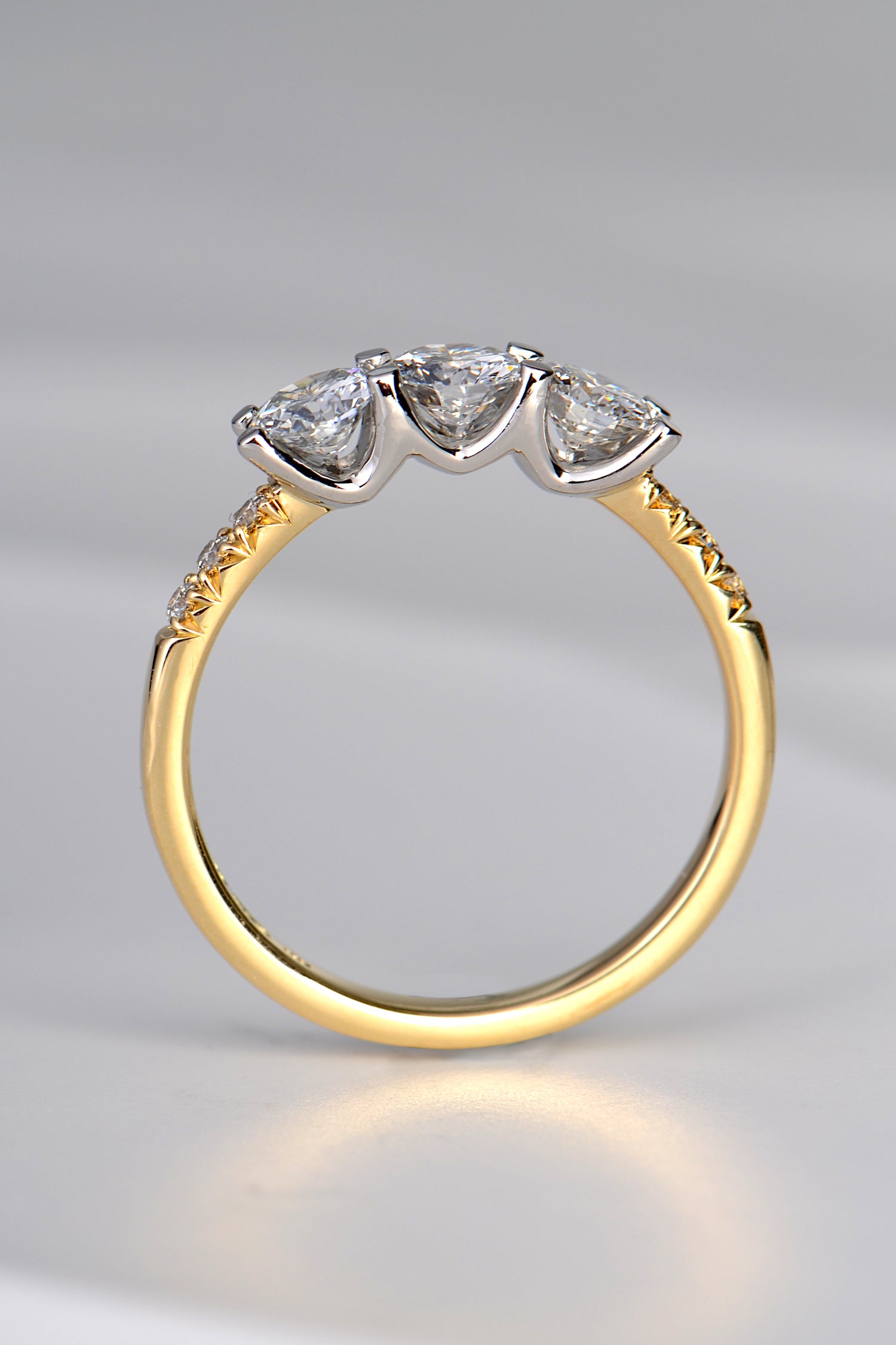 Side view of a three stone diamond ring in 18ct yellow gold and platinum made using a customer's diamonds from her old engagement ring to modernise the style 
