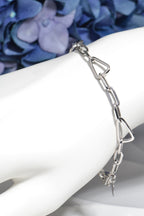 stylish triangle link bracelet in silver for a woman or girl shown on a white mannequin wrist with blue flowers in the background