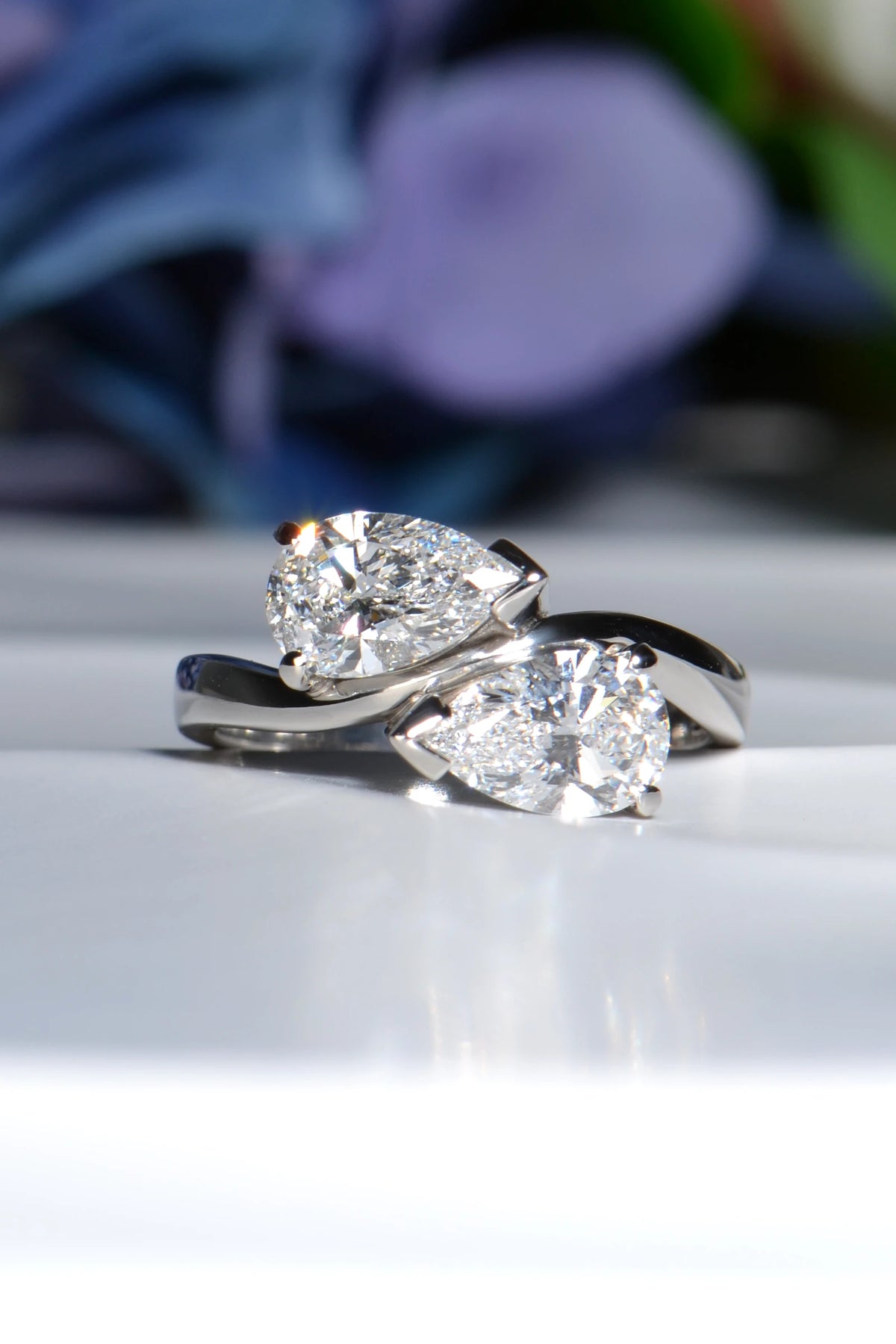 Front view of a bespoke platinum wave ring set with two matching one-carat pear cut lab diamonds.  Christine Sadler