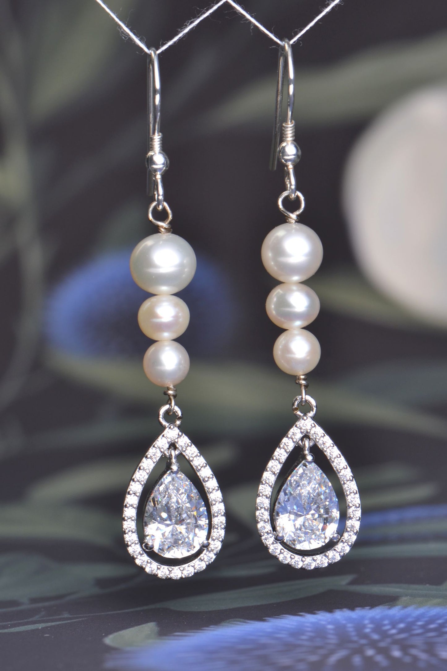 Long silver hook earrings with graduated cultured pearls and pear-shaped AAA cubic zirconia halo drops, 58mm length.