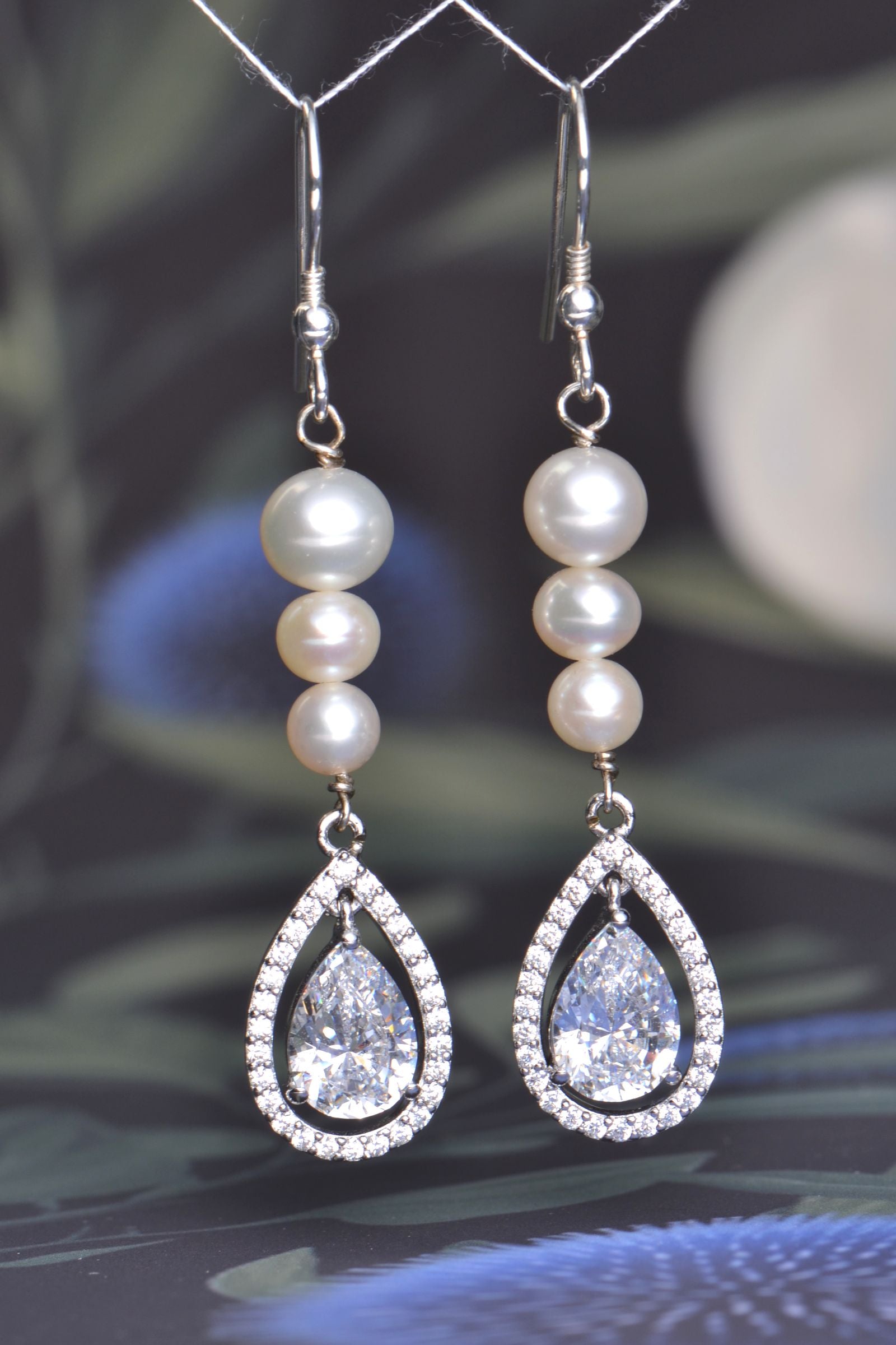Long silver hook earrings with graduated cultured pearls and pear-shaped AAA cubic zirconia halo drops, 58mm length.