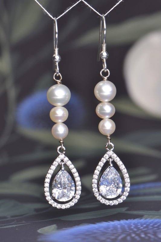 Long silver hook earrings with graduated cultured pearls and pear-shaped AAA cubic zirconia halo drops, 58mm length.