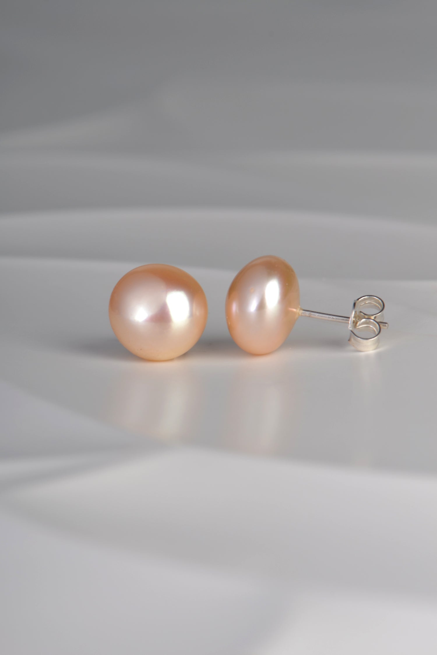 10mm peach pearl earrings photographed side on to show sterling silver posts and butterfly fittings
