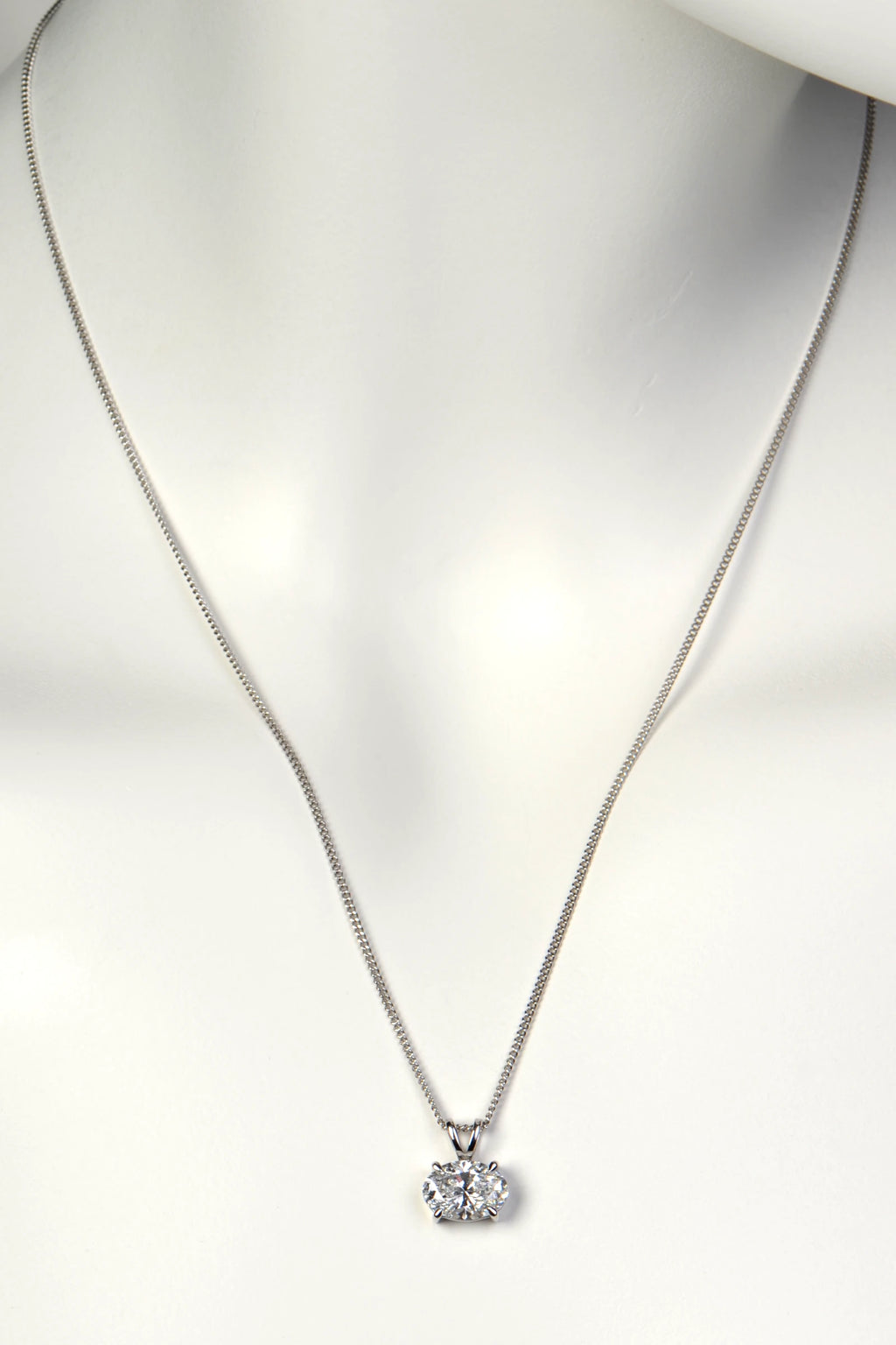 An East-West oval diamond pendant necklace worn on a white mannequin to show size, scale, and placement on the neckline. Christine Sadler
