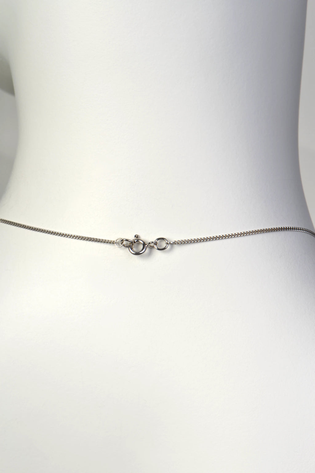 Detailed close-up of a small, discrete 9ct white gold bolt ring clasp on a fine curb chain. Christine Sadler